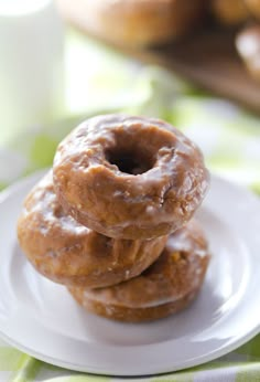 three glazed donuts stacked on top of each other on a white plate with green napkin