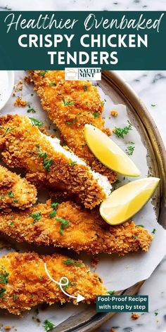 fried crispy chicken tenders on a plate with lemon wedges and parsley