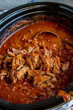 a slow cooker filled with meat and sauce