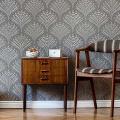 two chairs and a table in front of a wallpapered room with a clock