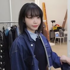 a young woman standing in front of a closet with clothes hanging on the rack and looking at the camera