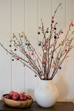 a white vase filled with branches and colorful balls