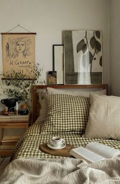 a coffee cup on a tray sitting on top of a bed next to an open book