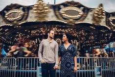 a man and woman standing in front of a merry go round