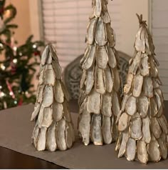 three small trees made out of seashells on a table next to a christmas tree