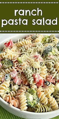 a pasta salad with broccoli and tomatoes in a white bowl on a green tablecloth