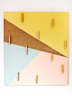 a cork board with clothes pins pinned to it and two different colored boards hanging on the wall