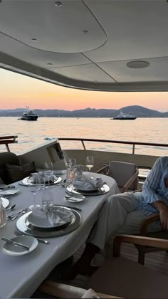 a man sitting at a table on top of a boat with plates and silverware