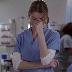 a woman in scrubs is holding her hand to her face and talking on the phone