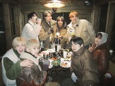 a group of people sitting around a table eating food and talking on cell phones in a room