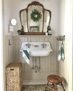 a white sink sitting under a bathroom mirror next to a wooden stool with a basket underneath it