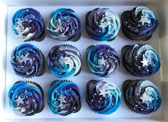 twelve cupcakes in a white box with blue frosting and stars on them