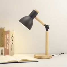 an open book on a table next to a desk lamp