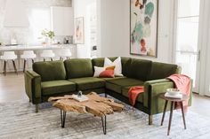 a living room with green couches and white chairs in front of a painting on the wall