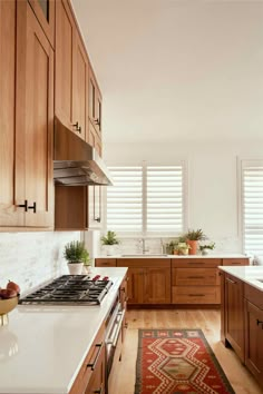 a kitchen with wooden cabinets and white counter tops, along with a rug on the floor