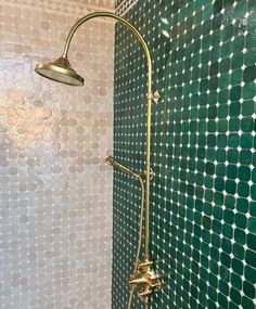 a shower head and hand shower in a bathroom with green tiles on the wall behind it