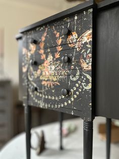 a black painted dresser with drawers and knobs on it's sides in a room