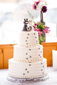 a three tiered wedding cake with black and white cat figurines on top