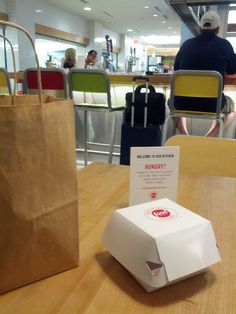 a paper bag sitting on top of a wooden table next to a box with a sign