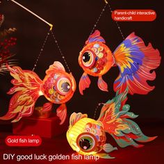 three colorful paper fish on display in front of a dark background with text that reads goldfish lamp dy good luck fish lamp