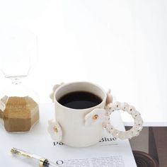 a cup of coffee sitting on top of a table next to a pen and paper