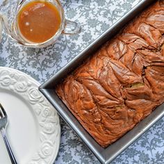 a loaf of bread sitting on top of a pan next to a cup and saucer