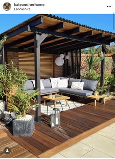 an outdoor living area with couches, tables and plants on the wooden decking