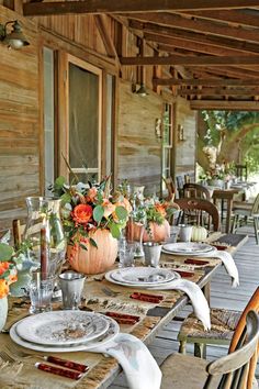 an outdoor dining area with wooden tables and chairs set up for dinner on the porch