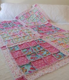 a pink and blue quilt on top of a bed