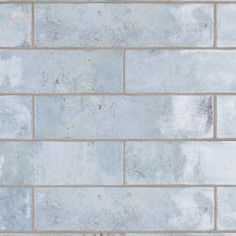 a white brick wall that has been painted blue and gray with some paint on it