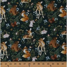 an animal print fabric with deers and flowers on the ground, in front of a ruler