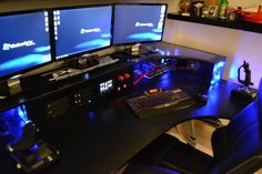 three computer monitors sitting on top of a desk next to a keyboard and monitor screen