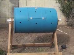 a large blue barrel sitting on top of a wooden stand next to a brick wall