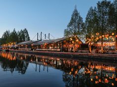 an outdoor dining area next to the water with lanterns hanging from it's roof