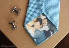 a blue tie with a photo on it next to two silver cufflinks and a pair of earrings