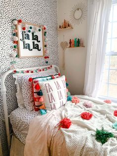 a white bed topped with lots of pillows next to a wall covered in polka dots