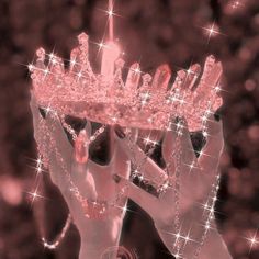 a woman wearing a pink tiara and holding her hands up to the sky with stars on it