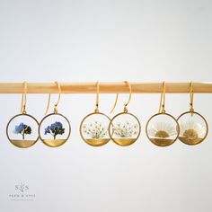 four different types of earrings hanging from a wooden rack with flowers in them on it