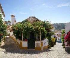 an alley way with flowers growing on the buildings and trees in the area around it