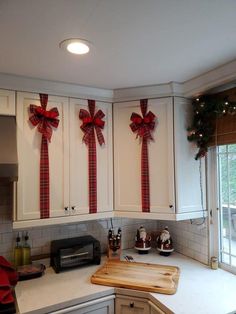 a kitchen decorated for christmas with bows on the cabinets