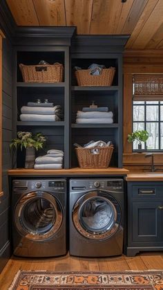 a washer and dryer in a room with wooden floors, dark blue cabinets and wood flooring