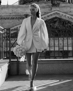 a woman is walking down the street wearing a white jacket and shorts with pom - poms