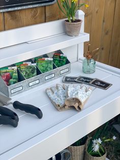 gardening tools are sitting on top of a white table in front of a wooden fence