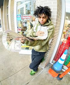 a young man with dreadlocks is holding an umbrella in front of a store