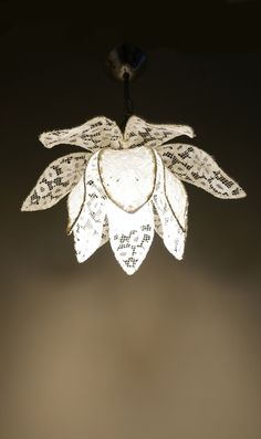 a white flower hanging from the ceiling with writing on it's petals and leaves