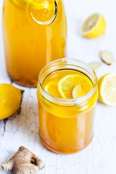 two mason jars filled with lemonade and ginger syrup next to some sliced lemons