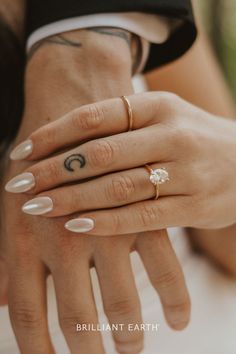 two people with rings on their fingers holding each other's hands and one is wearing a diamond ring