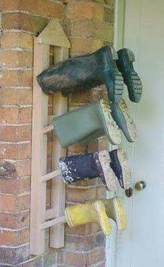 several pairs of shoes are hanging on a brick wall next to a door with a ladder