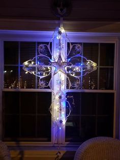 a lighted cross in front of a window