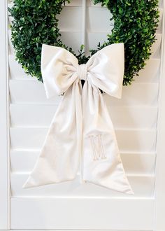 a white door with a wreath on it and a monogrammed bow hanging from the front